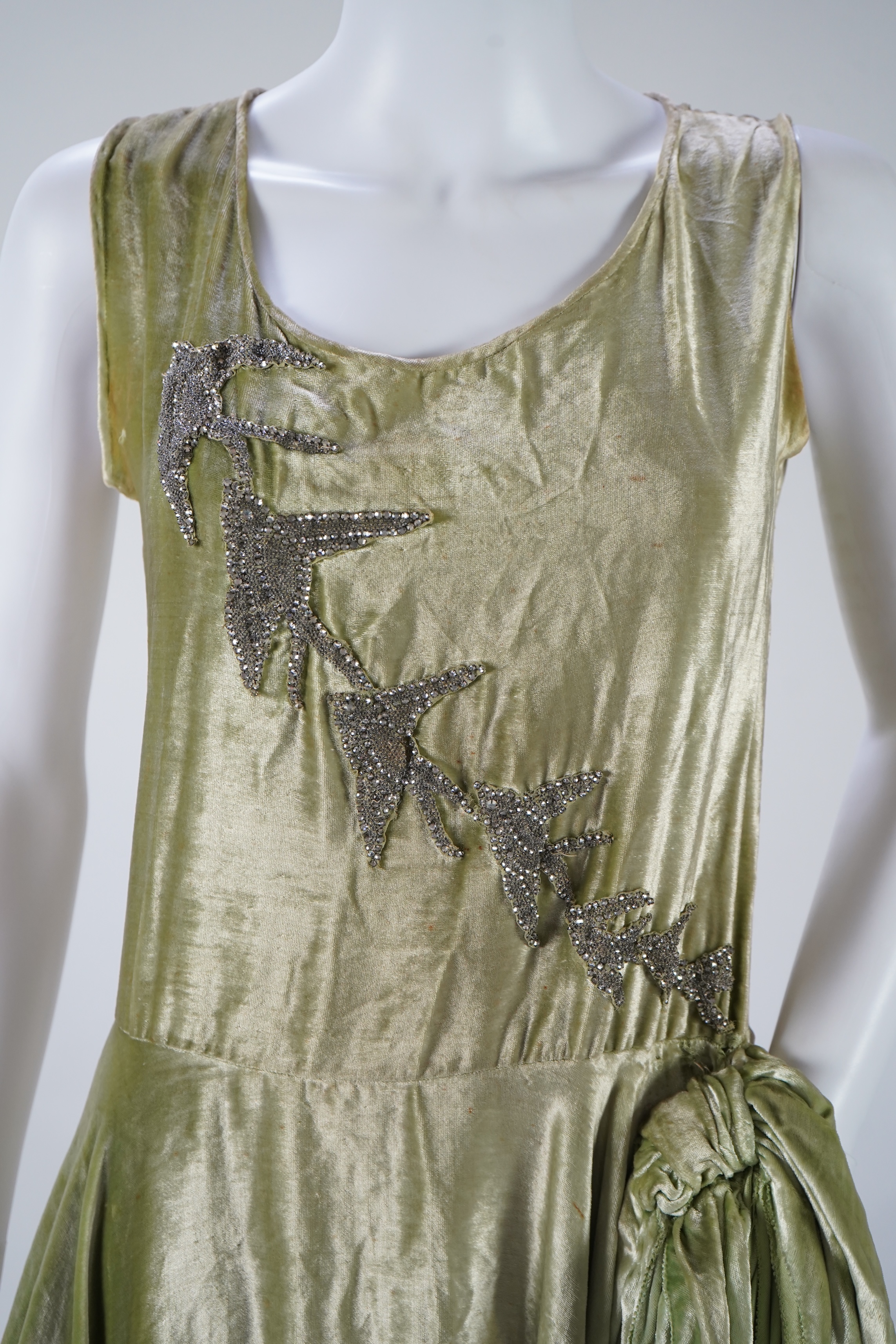 A late 1920’s early 30’s green panne silk velvet evening dress, bias cut, with large diamanté ornamentation and bow on the hip, bust 36 inches, length 55inches. Condition - there is a small hole on the front near arm hol